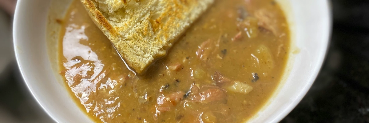 A bowl of hock soup pea soup with toasted bread on top